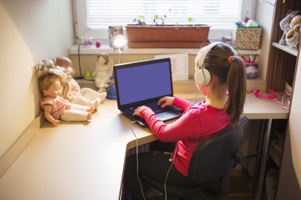 Menina com fone de ouvido na frente do computador estudando
